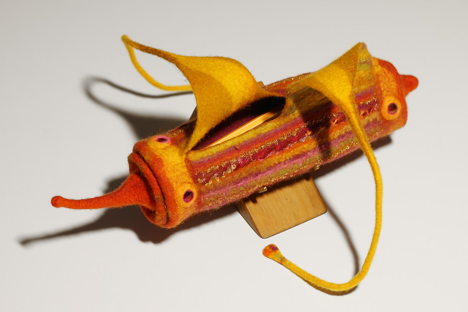 Filtat fodral i gult och orange med lite guldglitter och två remmar att stänga det med av Márti Csille.
<p>Felted case in yellow and orange with some glittering gold, and two straps to close it with by Márti Csille." class="wp-image-1310"><figcaption class=