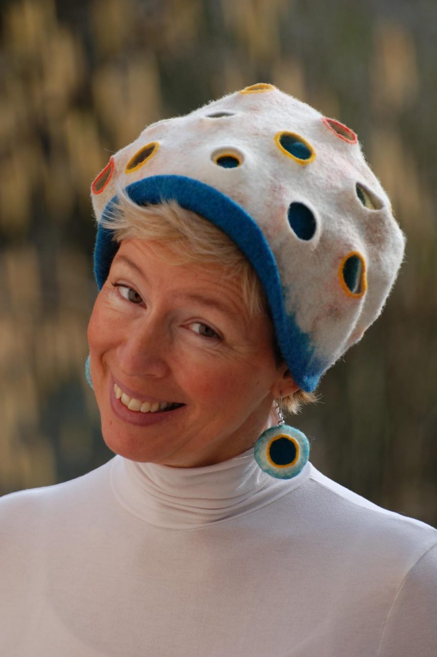 Kinga Huszti in one of her double walled felted hats. White on the outside, with holes rimmed in different colors, and blue color on the inside layer.
