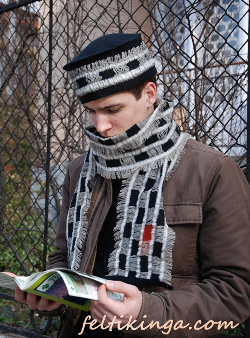 Young man reading with a black hat with white fabric inlays and a scarf that matches..